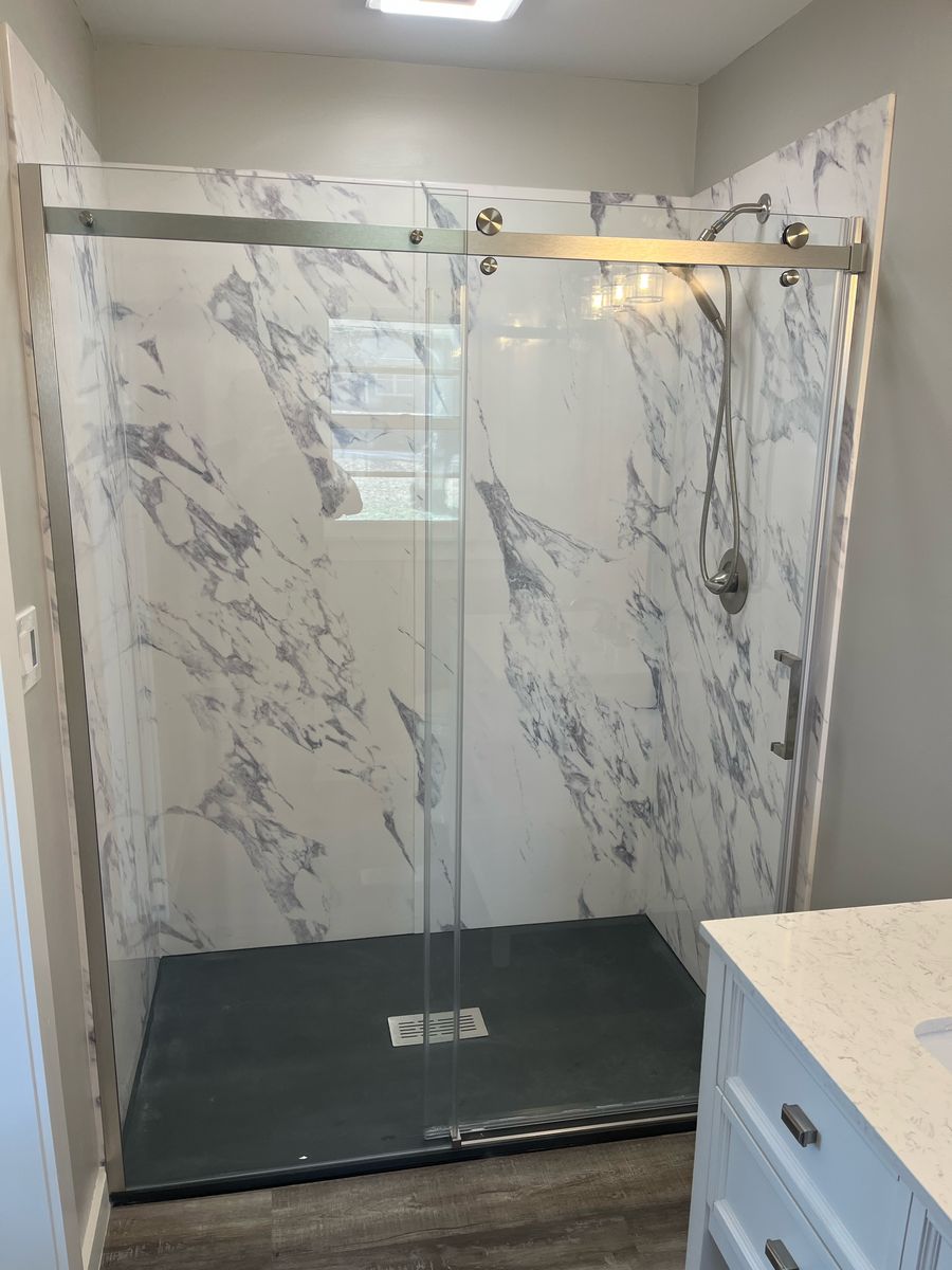 Walk-in shower with marble-look wall panels and a sliding glass door